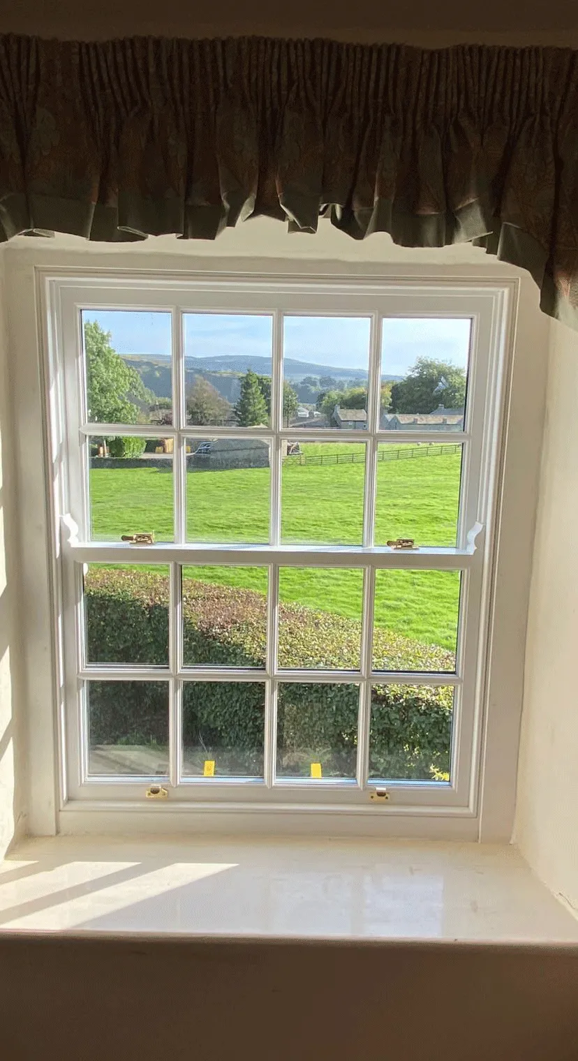 A window with a view of a green field.