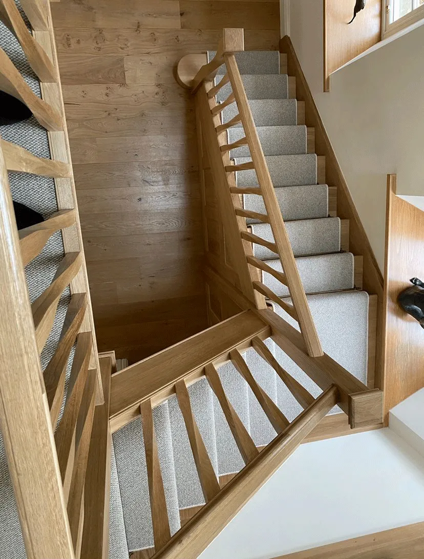A wooden staircase with carpeted steps leading to a second floor.